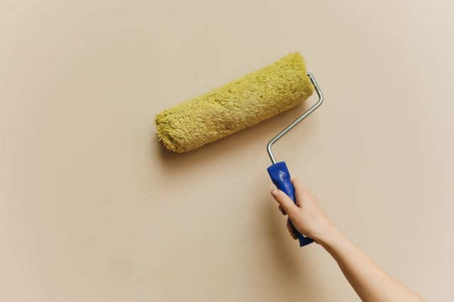 person holding a paint roller against a wall